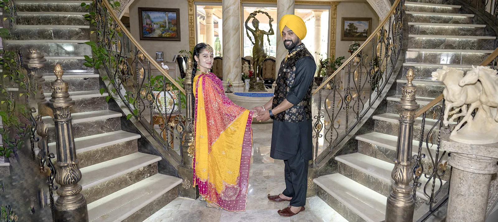 Couple posed on an indoor staircase before a celebration.